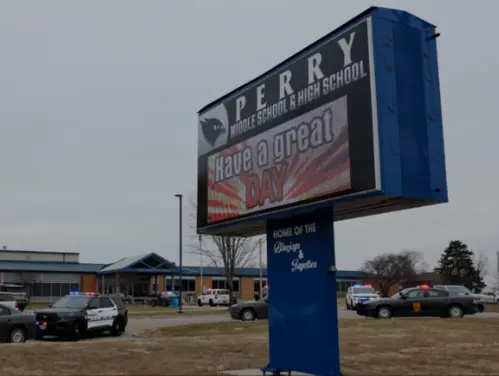 Perry High School sign outside of the school surrounded by police cars.