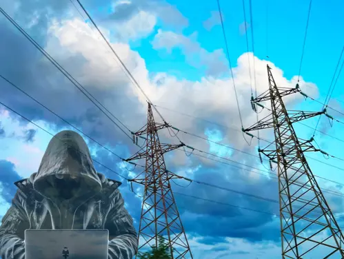 High voltage power lines in background with suspicious man hoodie typing on laptop