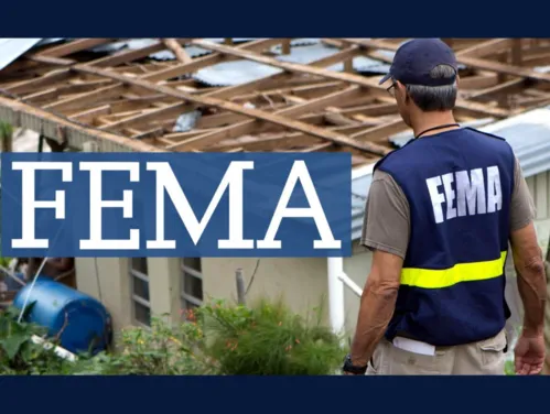 Man in FEMA vest assessing building with tornado damage.