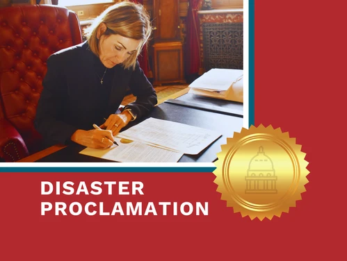 Gov. Reynolds signs disaster proclamation at her desk.