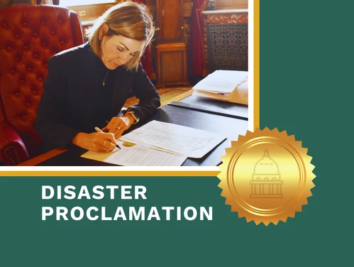 Gov. Reynolds signs disaster proclamation at her desk.
