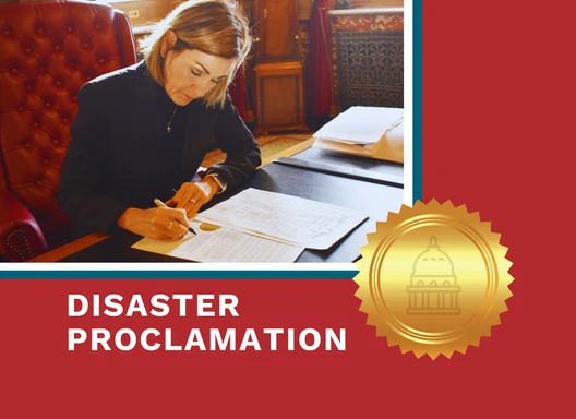 Gov. Reynolds signs disaster proclamation at her desk.