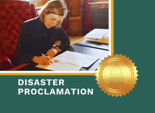 Gov. Reynolds signs disaster proclamation at her desk.