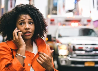 Woman is approached by ambulance as she talks on her cell phone on a city street..