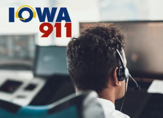 911 dispatcher looks at monitor, Iowa 911 logo.