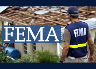 Man in FEMA vest assessing building with tornado damage.
