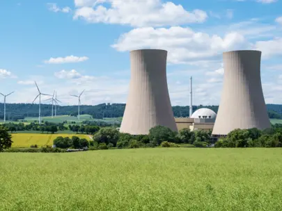 Nuclear Power Plant surrounded by green grass and wind turbines.