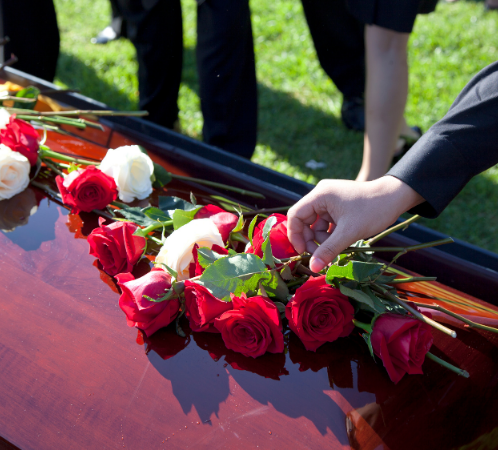 Hand placing rose on casket